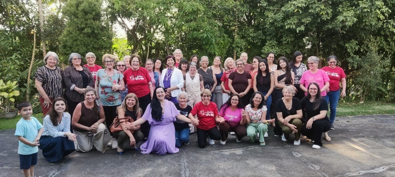 Foto de grupo das participantes ao ar livre diante das árvores