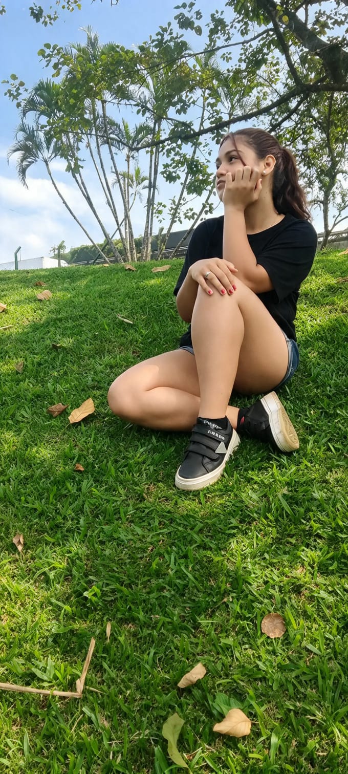 Ensaio externo — sentada no gramado entre palmeiras