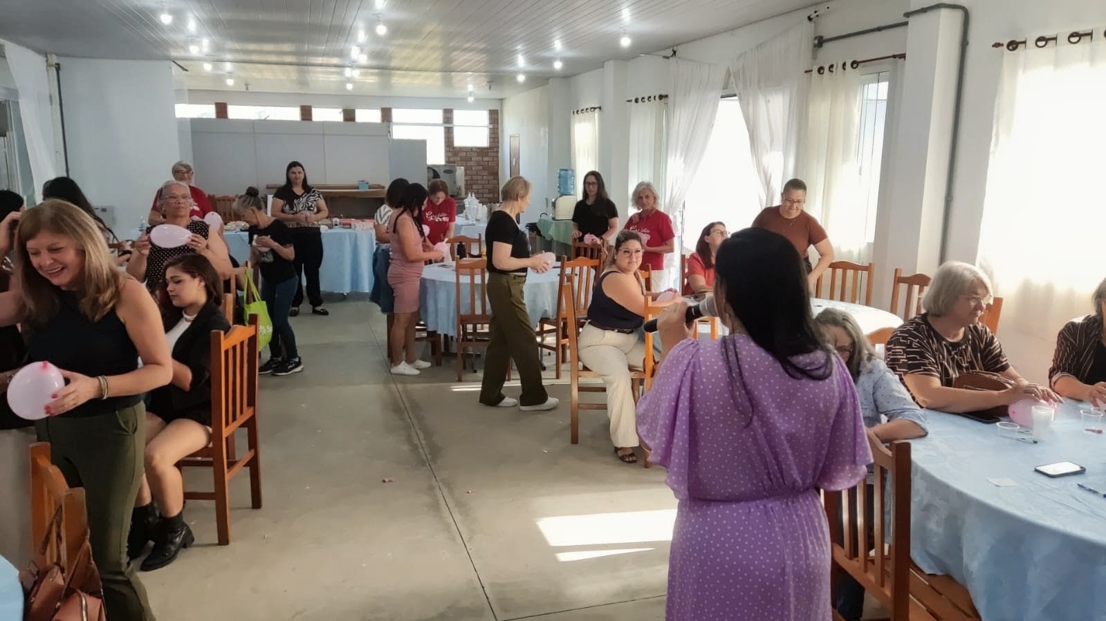 Organizadora com microfone conduzindo a dinâmica com as participantes