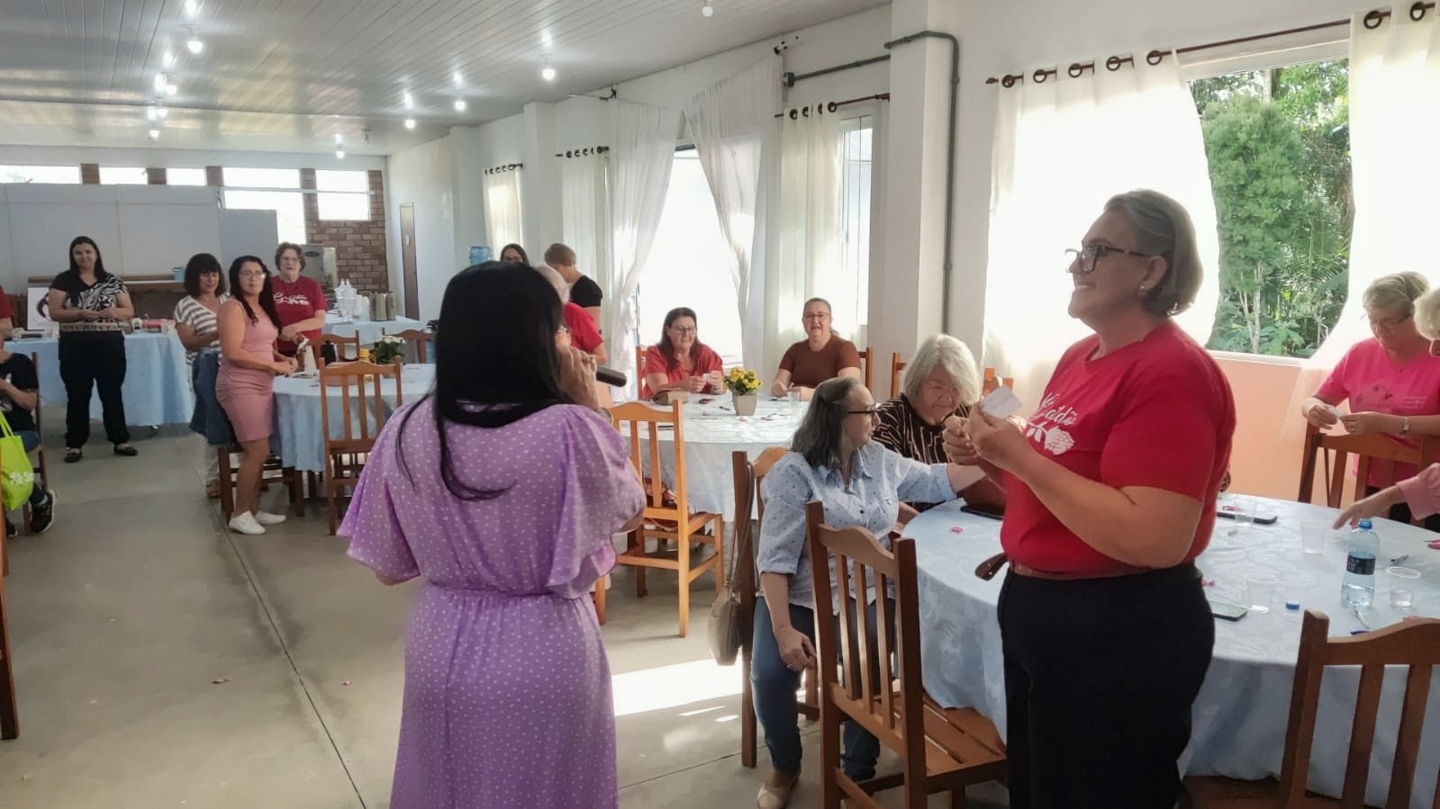 Organizadora com microfone conversando com participante sorridente