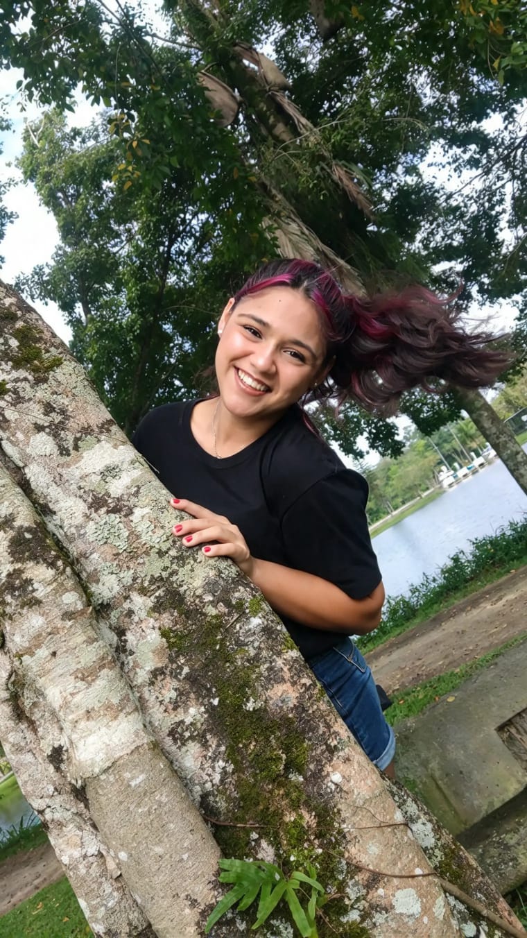 Ensaio externo — sorrindo entre os troncos de uma árvore